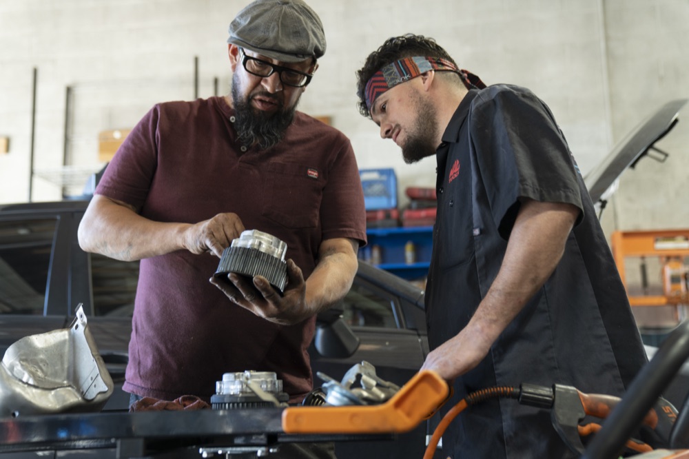 Adam Griego and a technician examining a Subaru component in the shop